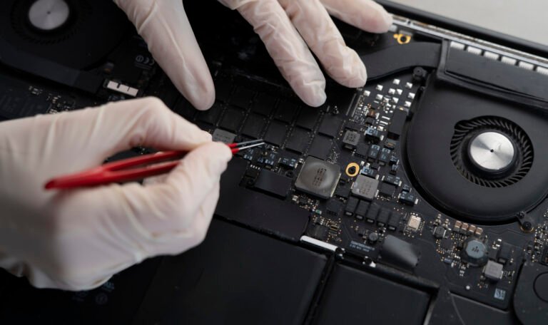 computer fixing service, master with tweezers repair laptop in the workshop